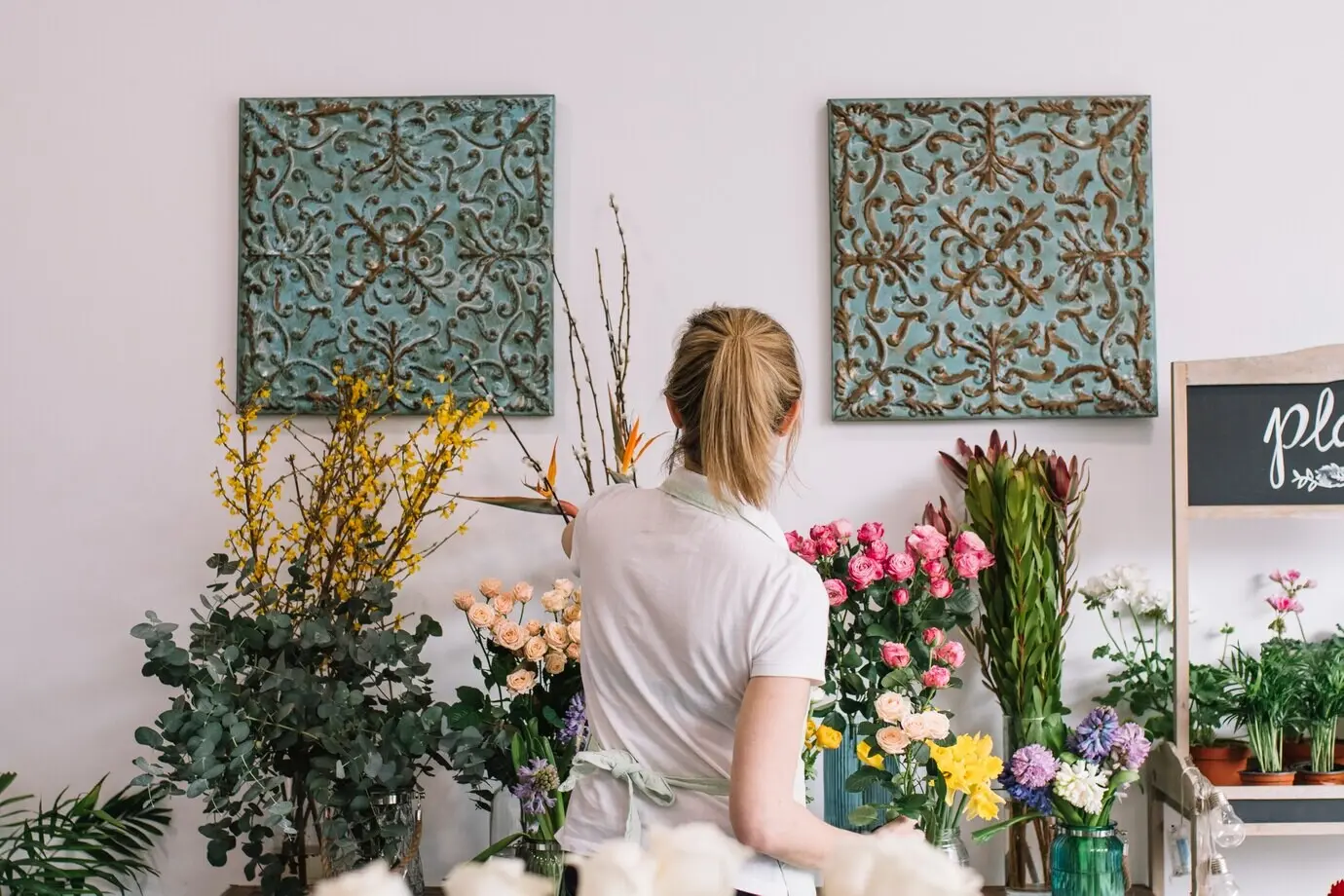 Rückansicht eines Floristen, der Blumen pflegt.