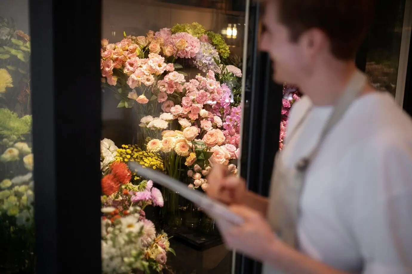 Junger männlicher Florist macht Notizen über die Blumen im Laden.